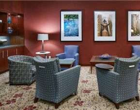 Hotel lounge, with armchairs and coffee tables, plus art on the wall.