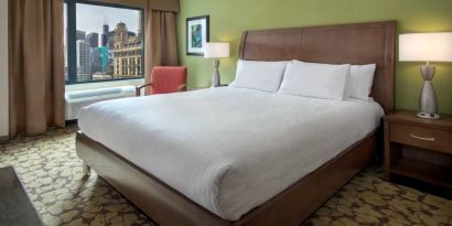 Double bed guest room within the Hilton Garden Inn Chicago Downtown Riverwalk, with city views through the large window.