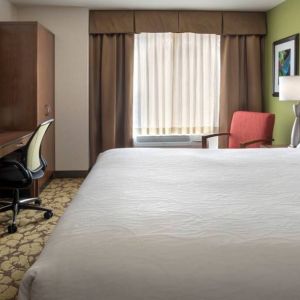 Guest room in the Hilton Garden Inn Chicago Downtown Riverwalk, including large bed, window, and desk and chair for working.
