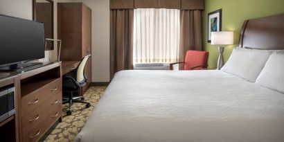 Guest room in the Hilton Garden Inn Chicago Downtown Riverwalk, including large bed, window, and desk and chair for working.