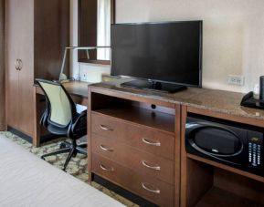 Closer view of an in-room workspace, with chair and desk for business, and both a lamp and window nearby.