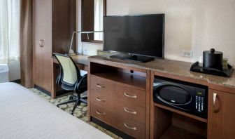 Closer view of an in-room workspace, with chair and desk for business, and both a lamp and window nearby.