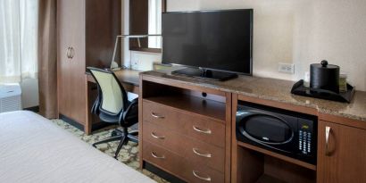 Closer view of an in-room workspace, with chair and desk for business, and both a lamp and window nearby.