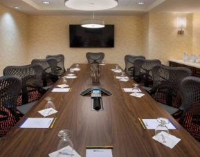 Meeting room in the Hilton Garden Inn Chicago Downtown Riverwalk, with long table, surrounding chairs and large TV.