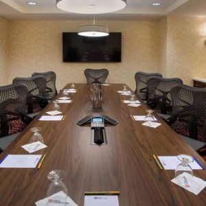 Meeting room in the Hilton Garden Inn Chicago Downtown Riverwalk, with long table, surrounding chairs and large TV.