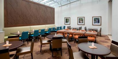 The hotel restaurant offers on-site dining, with varying table sizes and a bright and airy environment.