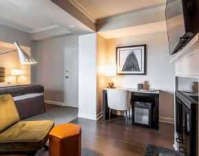 Guest room in Claridge House, featuring large bed, TV, and workspace desk and chair.