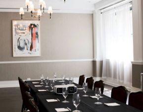 One of the hotel’s meeting room facilities, with long table, surrounding chairs, art on the wall, and large window.