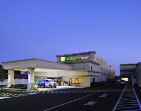 The exterior of the hotel, which provides shade/cover from the rain for the entranceway, and space for parking.