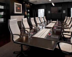 Stylishly dark meeting room, with long black table and white chairs around it.