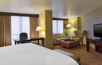 Double bed guest room in the Sheraton Houston Brookhollow Hotel, with sofa and large television.