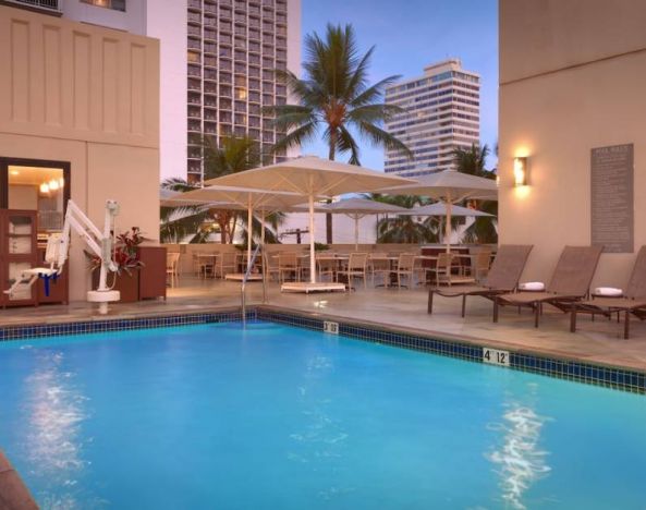 The hotel’s pool is outdoors and has loungers, tables, and chairs nearby.