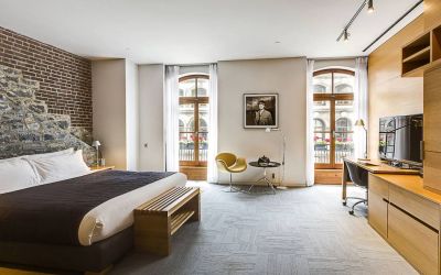 Double bed guest room in Hotel Gault, furnished with workspace desk and chair, plus large windows.