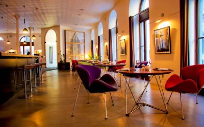 The hotel restaurant has a bar and small tables for diners to enjoy a refined breakfast experience.