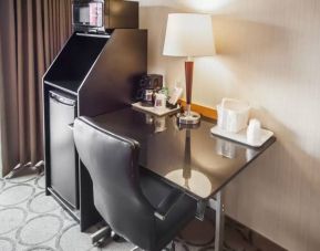 Closer shot of an in-room workspace, including chair, desk, lamp, and nearby window.