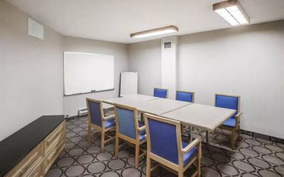 Hotel meeting room with space for half a dozen attendees around a table, and a whiteboard nearby.