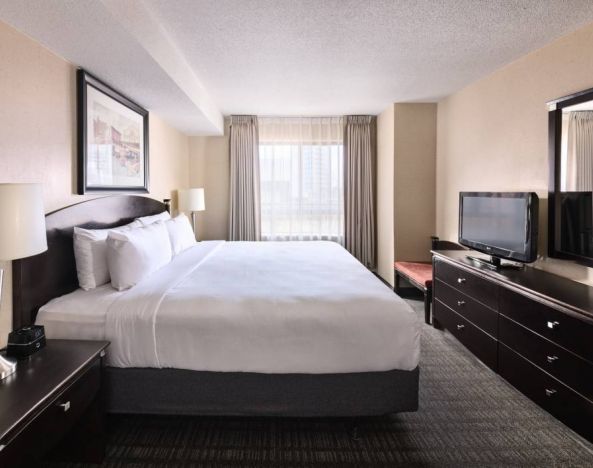 Double bed guest room in Les Suites Hotel Ottawa, with large window and TV.