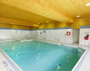 The hotel’s indoor pool is brightly lit and has chairs by the side.