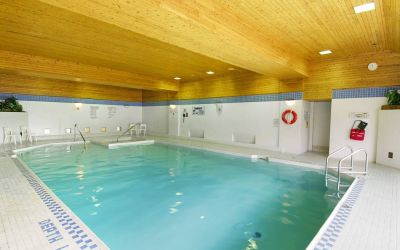 The hotel’s indoor pool is brightly lit and has chairs by the side.
