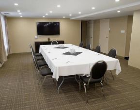 Meeting room in Les Suites Hotel Ottawa, with long table, ten chairs around it, and a large television.