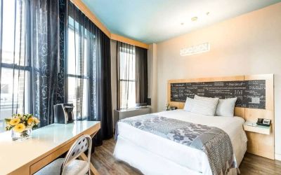 Room at the TRYP By Wyndham Times Square South containing desk, double bed, and large windows.