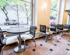 Econo Lodge Times Square’s breakfast area, with hard floor, tables for two, and large windows.