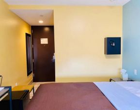 Bedroom at the Rodeway Inn Cranston JFK, with bedside table and wall-mounted safe.