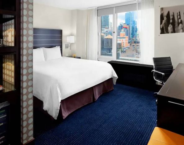 Guest room of the Hilton Fashion District, complete with king-sized bed and workspace desk and chair.