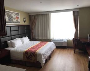 Queens Hotel guest room, including table, chair, window, and large double bed.