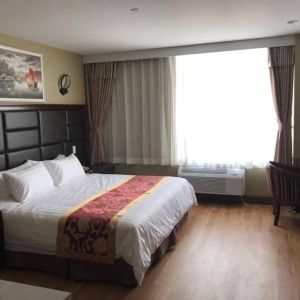 Queens Hotel guest room, including table, chair, window, and large double bed.