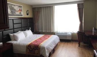 Queens Hotel guest room, including table, chair, window, and large double bed.