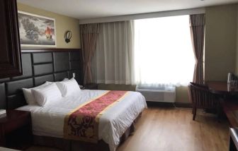 Queens Hotel guest room, including table, chair, window, and large double bed.
