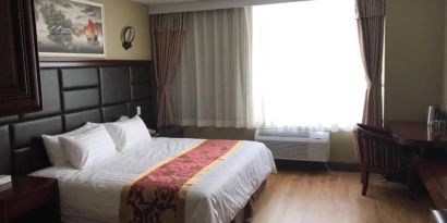 Queens Hotel guest room, including table, chair, window, and large double bed.