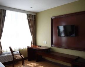 A Queens Hotel guest room with chair and table for working, and a nearby window.