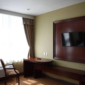 A Queens Hotel guest room with chair and table for working, and a nearby window.