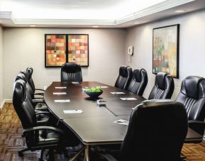 A meeting room with long wooden table and ten leather chairs around it.