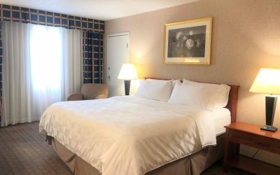 Double bed guest room in Holiday Inn Laval Montreal, with nearby chair and window.