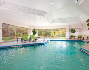 The hotel’s indoor swimming pool is brightly lit and has chairs and loungers by the side.