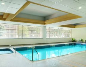 The hotel’s indoor pool is brightly lit and has chairs by the side.