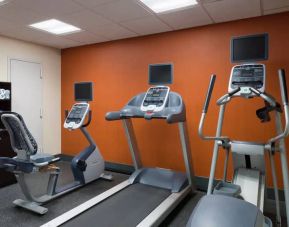 An exercise bicycle next to a treadmill and an elliptical machine in the Hampton Inn Manhattan - Madison Square Garden exercise room.