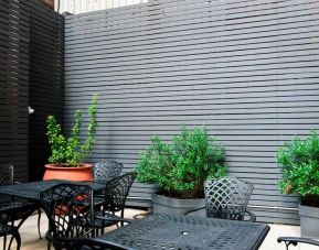 Patio with tall black privacy fences and black wrought iron tables and chairs for four people, at the Hampton Inn Manhattan - Madison Square Garden.