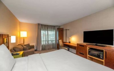 Double bed guest room in Comfort Inn Winnipeg Airport, with sofa and large window.