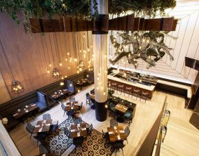 On-site restaurant and bar at Innside By Melia New York Nomad, with varying table sizes and bar stool seating.