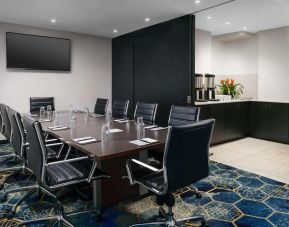 Hotel meeting room, with ten leather chairs surrounding a long table, and coffee-making facilities.