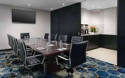 Hotel meeting room, with ten leather chairs surrounding a long table, and coffee-making facilities.
