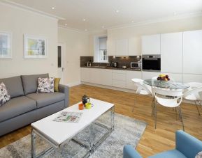 Wider view of the lounge and kitchen area, including sofa, table, and chairs.