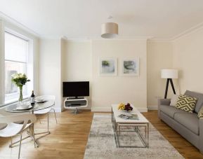 Lounge with sofa, coffee table and chairs, window, and widescreen television.