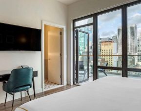 Guest room in The Draper, Ascend Hotel Collection, with TV and workspace desk and chair, plus city views.