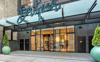 The hotel’s exterior, with The Draper, Ascend Hotel Collection’s name, awning, and large potted plants.