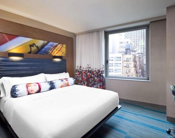 Double bed guest room in the Aloft Manhattan Downtown - Financial District, with art on the wall and large window.